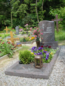 Grabstätte eines Urnengrabs aus Stein mit Pflanzenbesatz und Accessoires