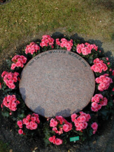 Kreisrunde Grabsteinplatte mit Blumen rundum